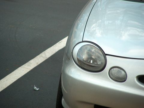1998 Ford Taurus - The front corner of a silver car is visible, a round headlight and a smaller fog light below.