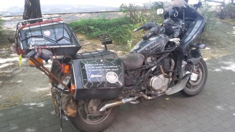Motorcycle with extensive luggage, custom paint, and a doll hanging from the rear