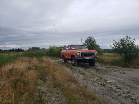 1978 Ford Bronco - Orange 1978 Ford Bronco on a dirt road under a cloudy sky.