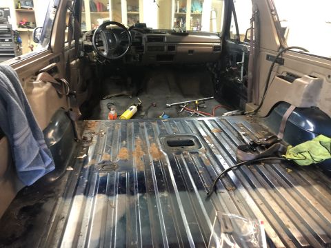 1995 Ford Bronco - The interior of the vehicle is being worked on, with seats removed and the floor exposed.