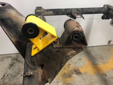 1992 Jeep Wrangler - Close-up of a yellow bushing mount on a heavily rusted vehicle frame part.