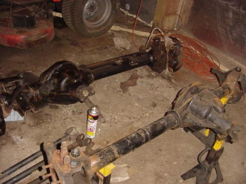 1992 Ford Bronco - Two vehicle axles are shown in a garage setting, with a lawnmower visible in the background.