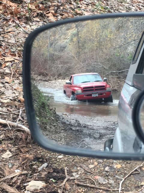 1996 Dodge 1500 - A red 1996 Dodge 1500 navigates through a water crossing on a dirt path.