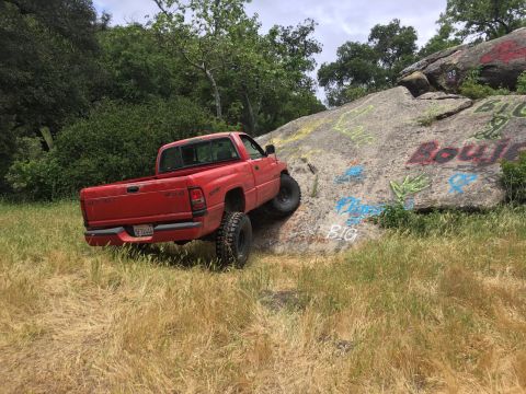 1996 Dodge 1500 - Red Dodge 1500 climbs a rocky incline with graffiti on the rocks.