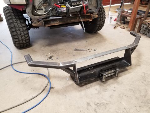 1996 Dodge 1500 - A custom steel bumper with a winch is laid out on a workshop floor, with a vehicle's front tire and chassis visible.