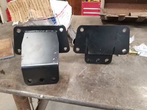 1996 Dodge 1500 - Two black metal brackets are shown on a workbench, with a box and tools in the background.