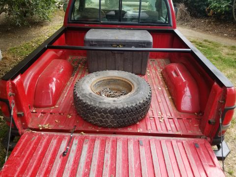 1996 Dodge 1500 - The bed of a red 1996 Dodge 1500 pickup truck contains a spare tire and a black toolbox.