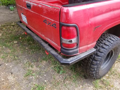 1996 Dodge 1500 - Rear view of a red 1996 Dodge 1500 pickup truck with an aftermarket bumper and large off-road tires.