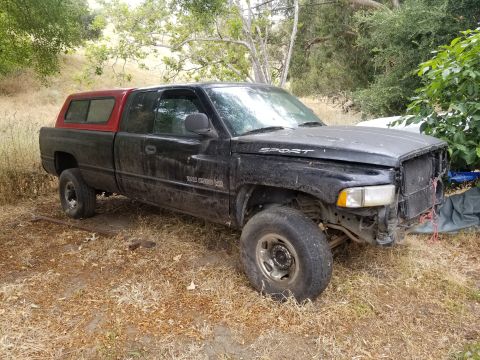 1996 Dodge 1500 - This 1996 Dodge 1500 pickup truck has a red camper shell and is missing its front grille.