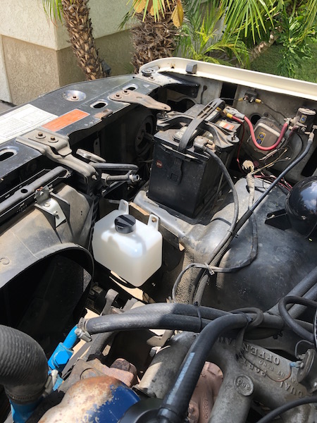 1981 Ford Bronco - The engine compartment shows various components including the battery and coolant reservoir, with some text visible on engine parts.