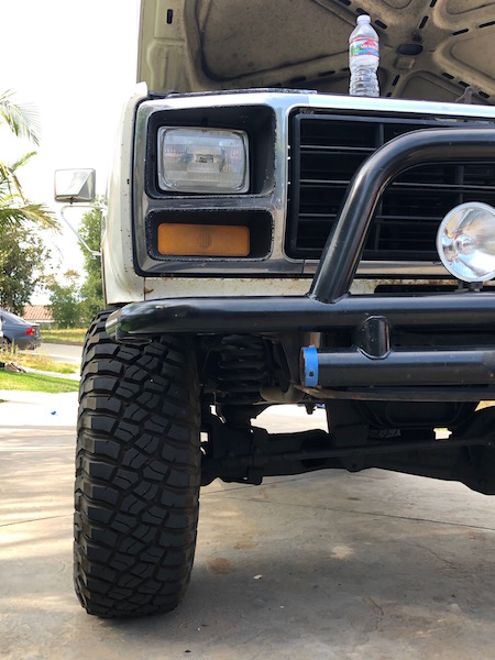 1981 Ford Bronco - Close-up of a white Ford Bronco's front end, showing off-road tires and a bull bar.