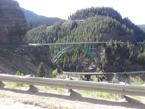 1999 Ford E250 - A scenic view of a large green arch bridge crossing a vast canyon, surrounded by dense pine forests and terrain.