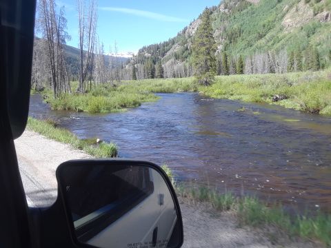 1999 Ford E250 - Reflection in a side mirror shows a vehicle traveling alongside a mountain stream.
