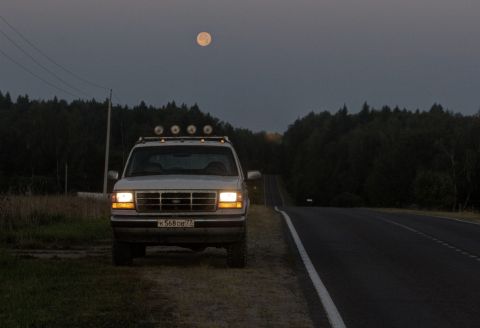 1993 Ford Bronco - Ford Bronco parked on roadside under a full moon, with trees and a road in the background.