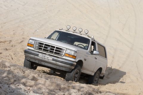 1993 Ford Bronco - This 1993 Ford Bronco navigates sandy terrain, equipped with auxiliary lights on its roof rack.