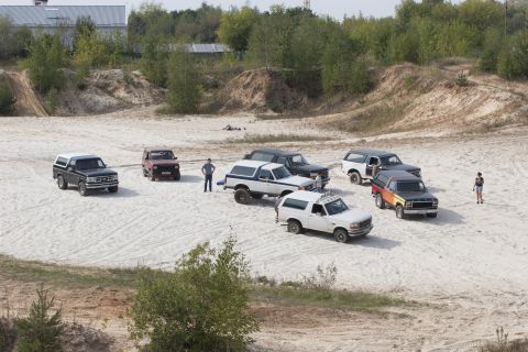 1993 Ford Bronco - Multiple Ford Bronco SUVs are gathered in an outdoor sandy area.
