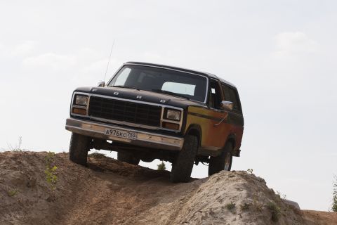 1993 Ford Bronco - A black and yellow Ford Bronco navigates an off-road course on a sunny day.