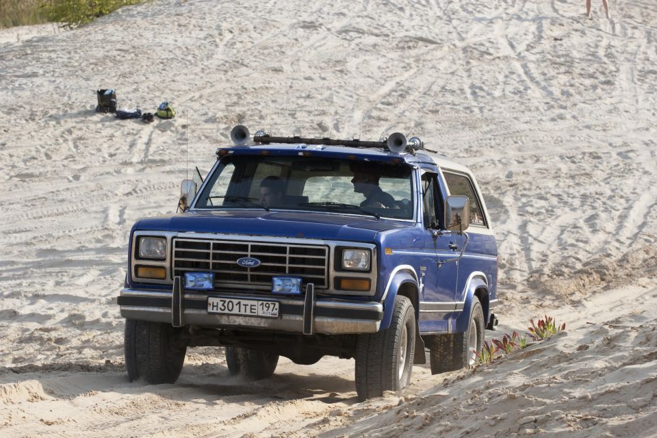 Blue Ford Bronco driving on a sandy hill. License plate H301TE 197