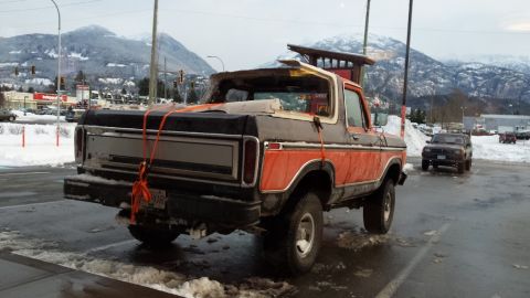 1978 Ford Bronco - This 1978 Ford Bronco is being transported with a wooden structure strapped to its roof in a snowy parking lot.