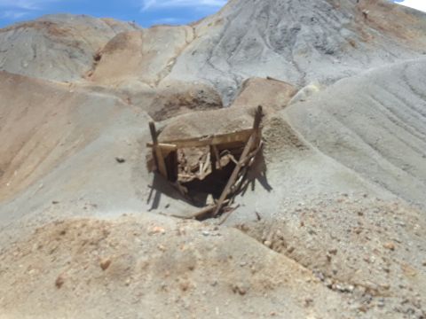 1999 Ford E250 - A derelict mine entrance sits in a desolate, rocky terrain, suggesting a forgotten past.