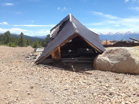 1999 Ford E250 - An old, dilapidated building sits in a rocky, high-altitude area with mountains in the background.