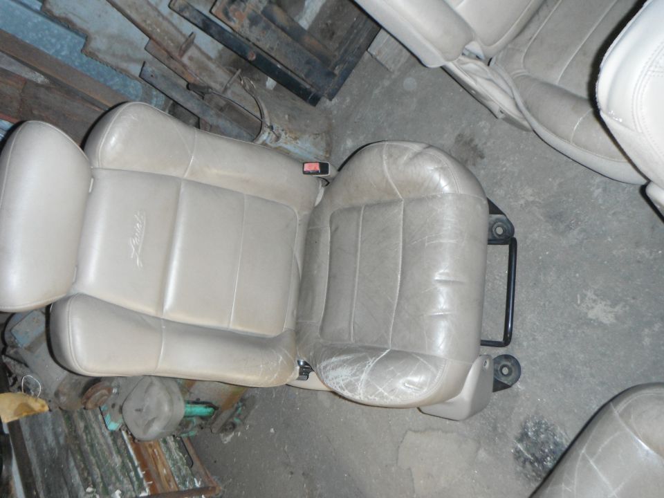 Two tan leather car seats, one with a faint embossed logo, are shown from above