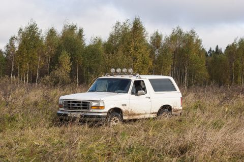 1993 Ford Bronco - This 1993 Ford Bronco navigates a muddy, overgrown field under a cloudy sky.