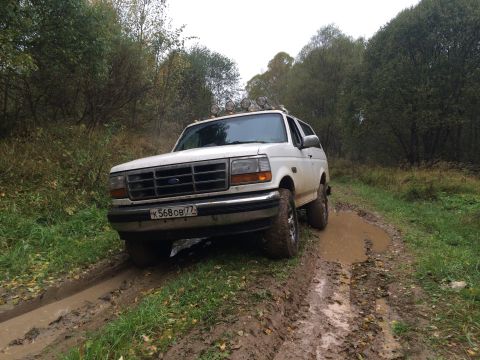 1993 Ford Bronco - This 1993 Ford Bronco navigates a muddy trail surrounded by trees.