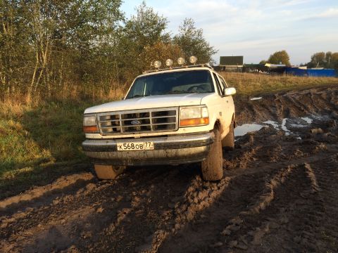 1993 Ford Bronco - This 1993 Ford Bronco is stuck in a muddy field, its front grille and roof lights visible.