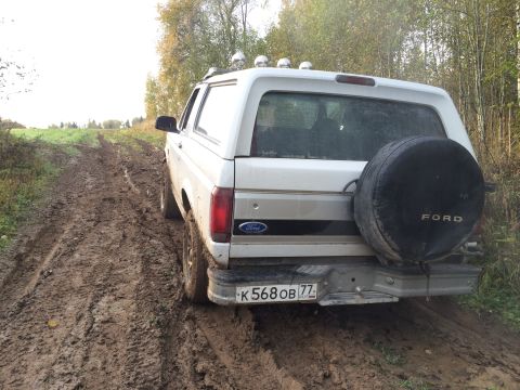 1993 Ford Bronco - White 1993 Ford Bronco navigates a challenging muddy terrain.