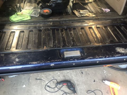 1995 Ford Bronco - The interior of a vehicle's tailgate area is shown, with various items scattered on the surface.