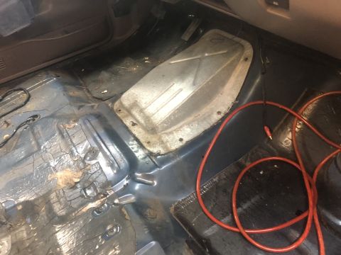 1995 Ford Bronco - Interior view of a vehicle's floor pan, showing a metal cover and a red cable. The registry information suggests it is a 1995 Ford Bronco,…