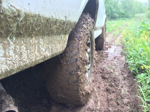 1993 Ford Bronco - A vehicle navigates a very muddy path, with tires and lower body panels heavily caked in mud.