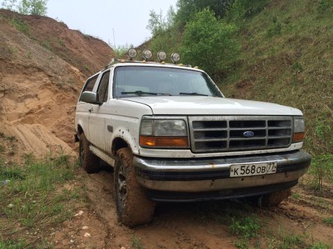1993 Ford Bronco - This 1993 Ford Bronco navigates a challenging muddy terrain, equipped with auxiliary lights on its roof rack.