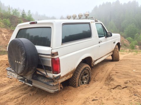 1993 Ford Bronco - White 1993 Ford Bronco stuck in sand with spare tire mounted on the rear.