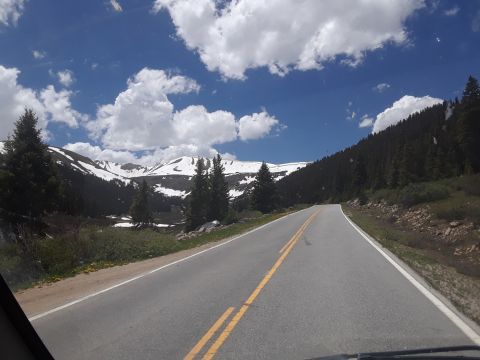 1999 Ford E250 - Driving on a scenic mountain road with snow on the peaks and a clear blue sky.