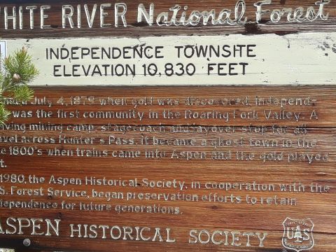 1999 Ford E250 - A wooden sign details the history of Independence Townsite, established in 1879, and its preservation efforts.