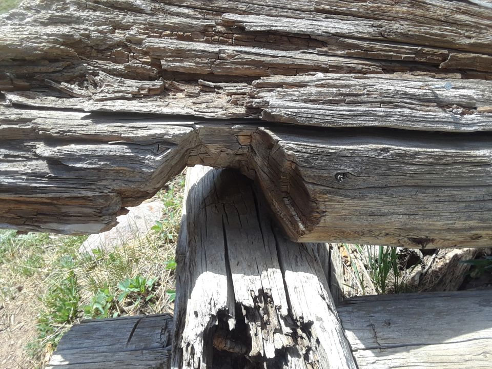 Weathered wooden fence with a gap showing grass and dirt. SuperMotors.net logo in lower right