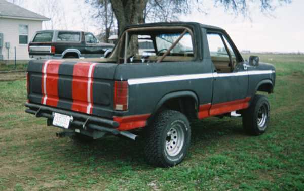 Rear three-quarter of a black and red striped lifted Ford Bronco on grass