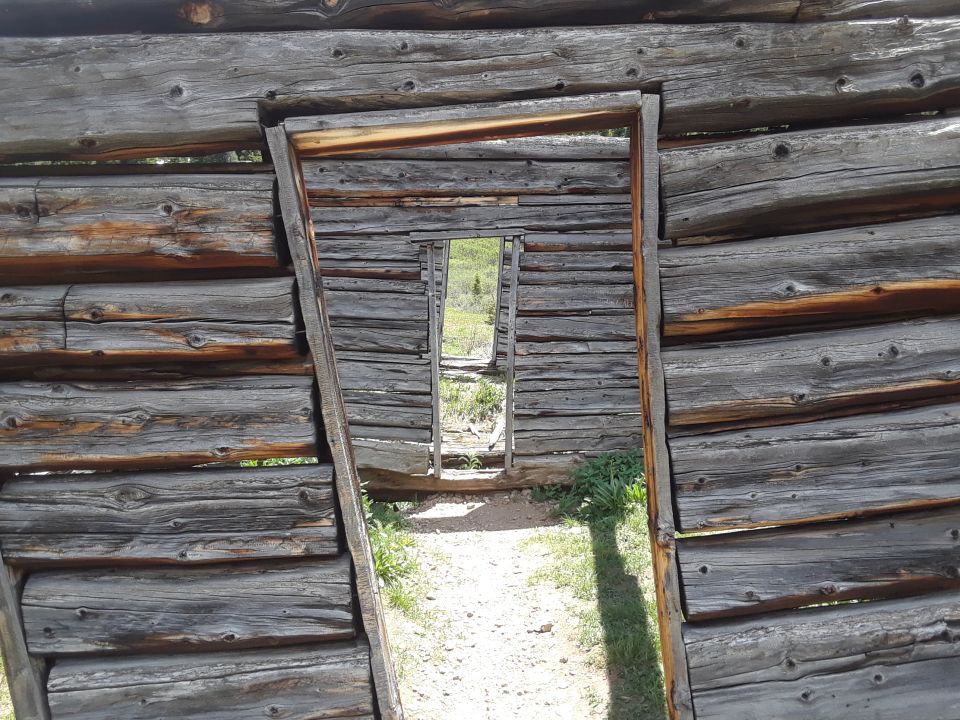 view through doorway of old log cabin, path leads outside