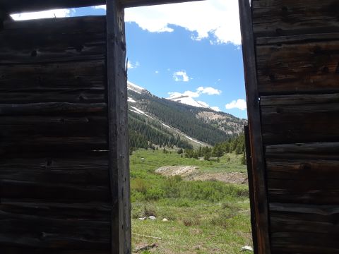 1999 Ford E250 - A scenic mountain vista unfolds beyond the weathered timbers of an old structure.