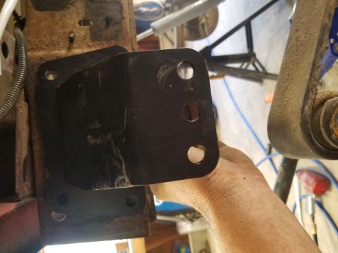 1996 Dodge 1500 - Close-up of a metal bracket being held against a vehicle's rusty frame.