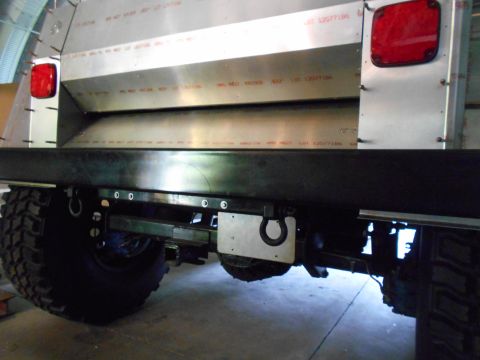 1992 Ford Bronco - The rear of a heavily modified vehicle shows custom metal fabrication and large, tires.