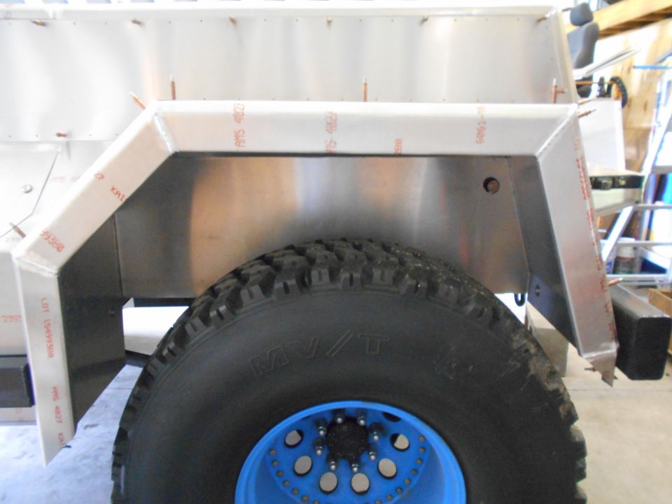 Rear wheel well and tire of a custom vehicle with aluminum paneling