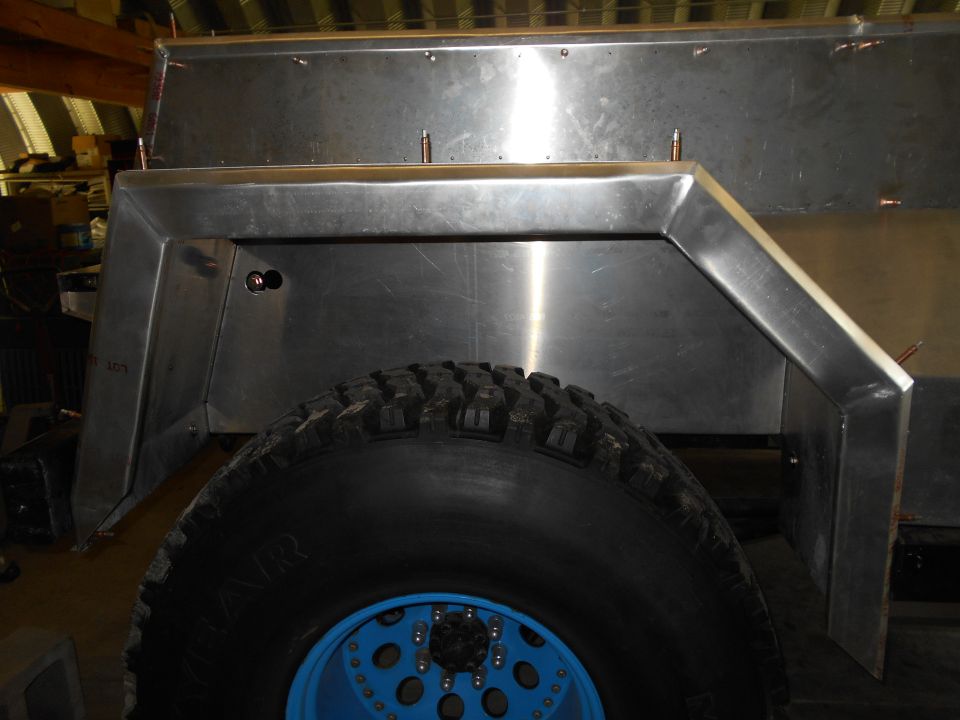 Close-up of a custom metal fender flare and tire on a vehicle, possibly under construction