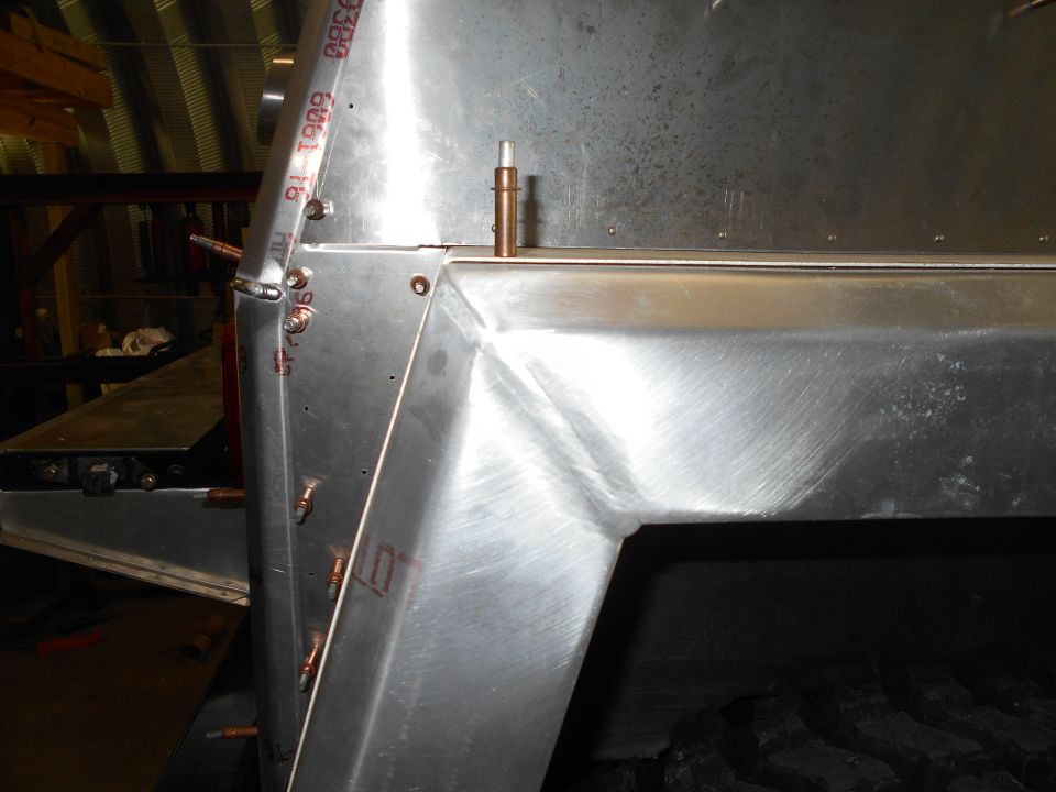 Metal frame section with rivets and copper fittings, showing brushed metal texture and some red markings