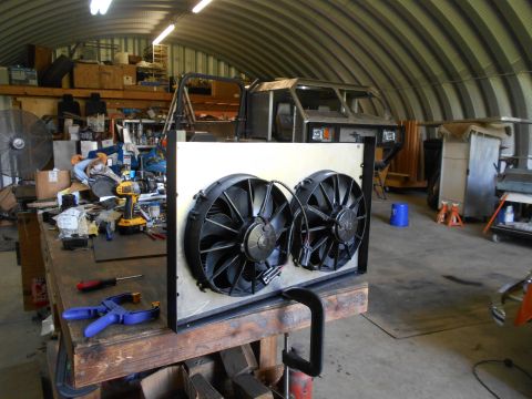 1992 Ford Bronco - Dual electric cooling fans are mounted on a frame in a workshop setting, with a vehicle chassis visible in the background.