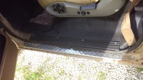 1990 Ford F-250 - The interior door sill area of a vehicle features a diamond plate trim piece and black floor matting.