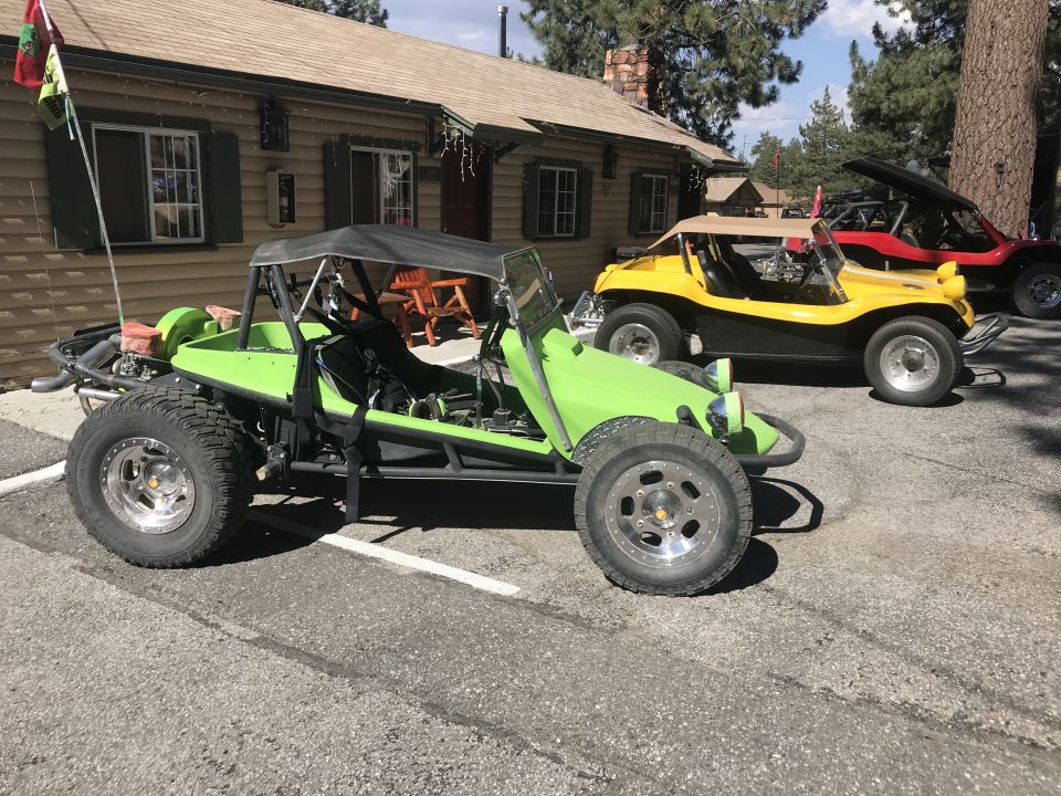Lime green dune buggy with black soft top, chrome wheels, and off-road tires parked next to a yellow dune buggy
