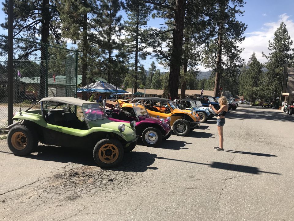 Line of colorful dune buggies parked on asphalt, woman taking photo